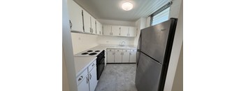 A kitchen with white cabinets and a black refrigerator.