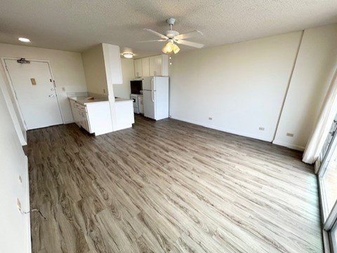 A room with a ceiling fan and wooden flooring.