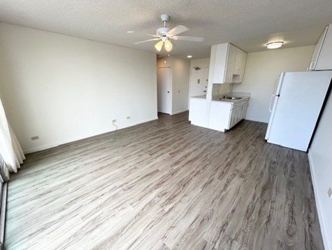A kitchen area with a refrigerator, sink, and cabinets.