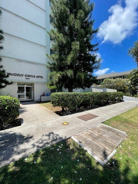 a sidewalk in front of a building with a tree