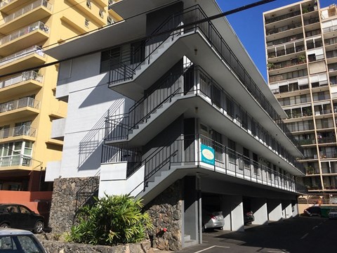 a building with three balconies and a parking lot