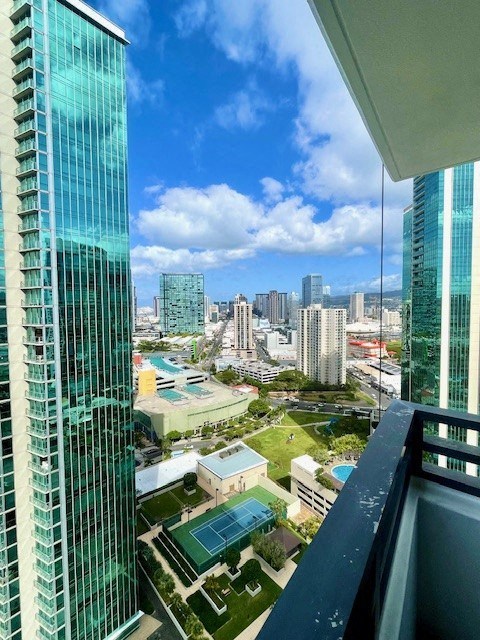 A view from a high-rise building looking down at a cityscape with a pool area in the foreground.