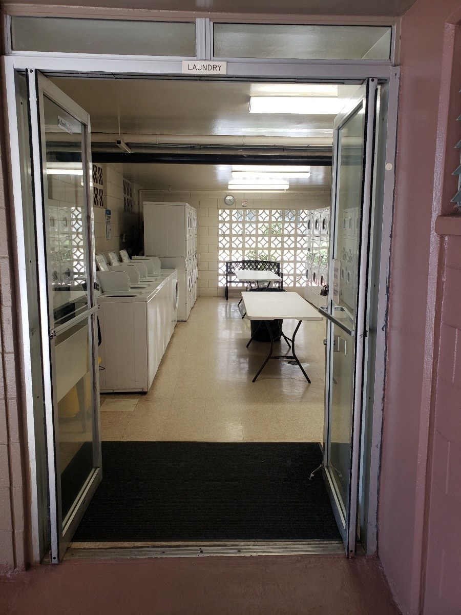 an open door leading into a room with washing machines and a table
