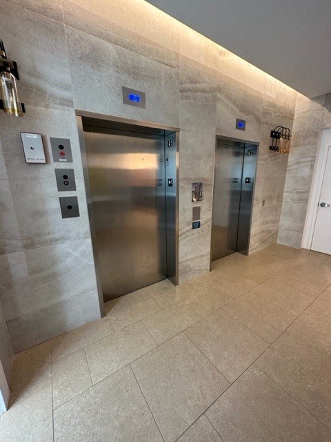 two stainless steel elevators in a large elevator lobby