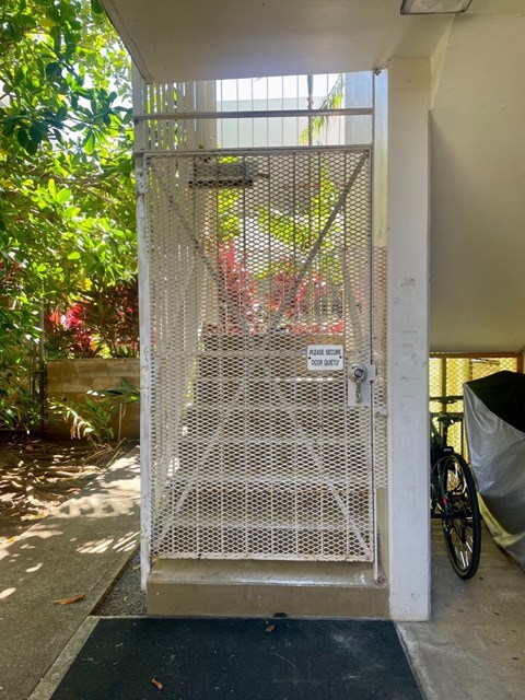 A metal gate with a keypad lock is open.