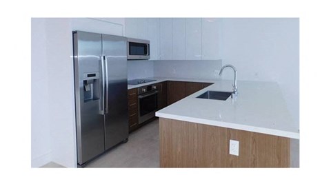 A kitchen with a stainless steel refrigerator and a white countertop.