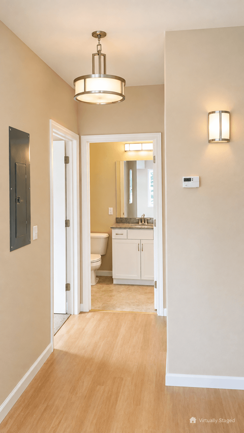 A hallway with a light brown wooden floor and white walls.