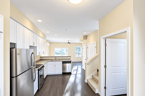 A kitchen with a refrigerator, cabinets, and a stove top oven.
