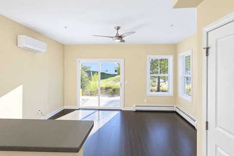 A room with a ceiling fan and sliding glass doors.