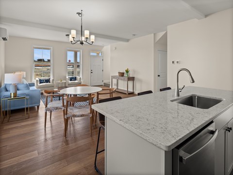 A kitchen with a marble countertop and a dining table with chairs.