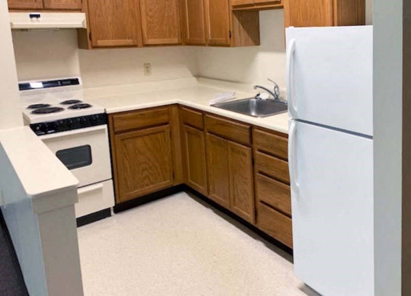 Country Park kitchen with refrigerator, stove and upper and lower storage cabinets