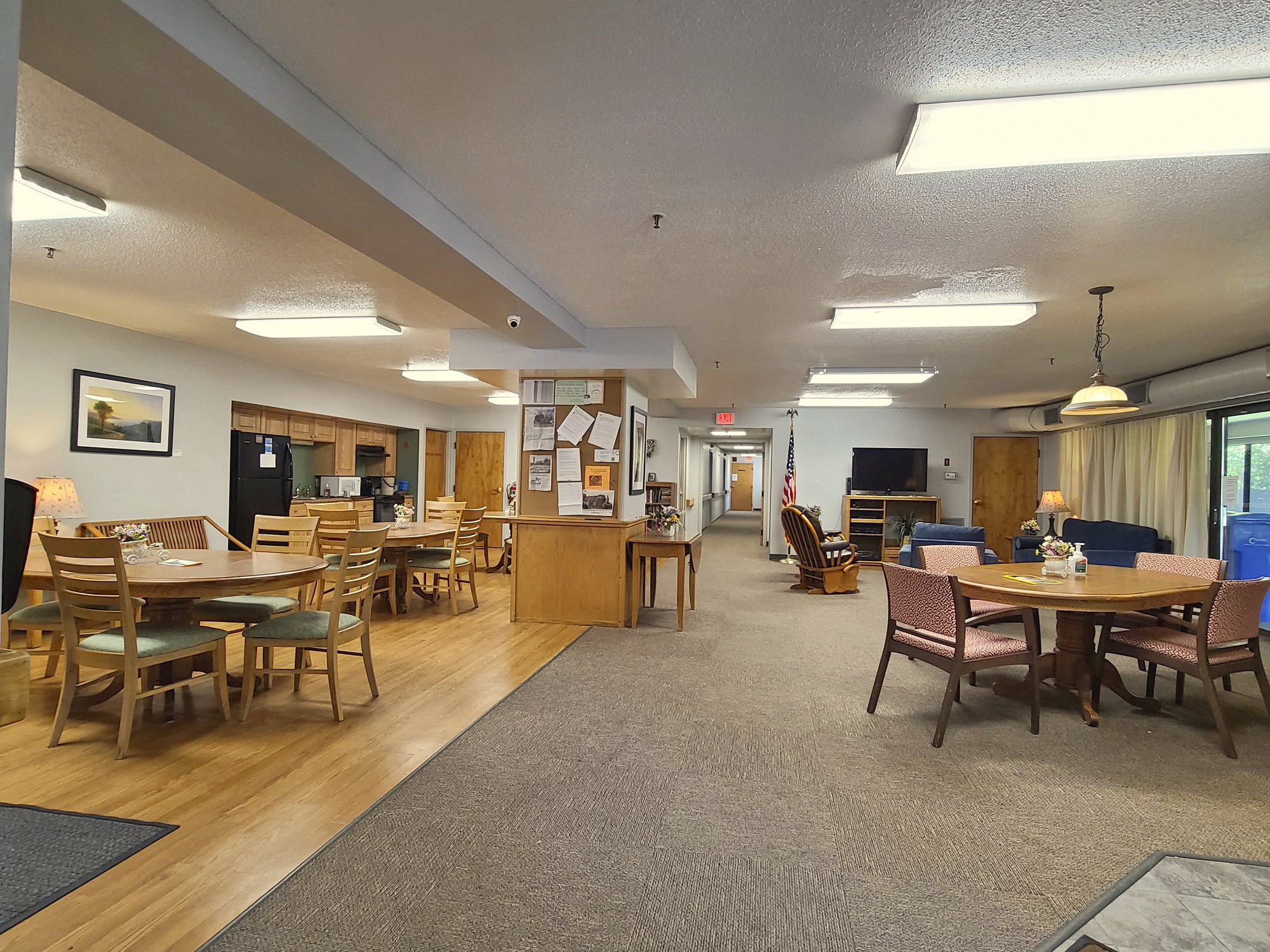 McKenzie House community room with tables, television and comfy chairs
