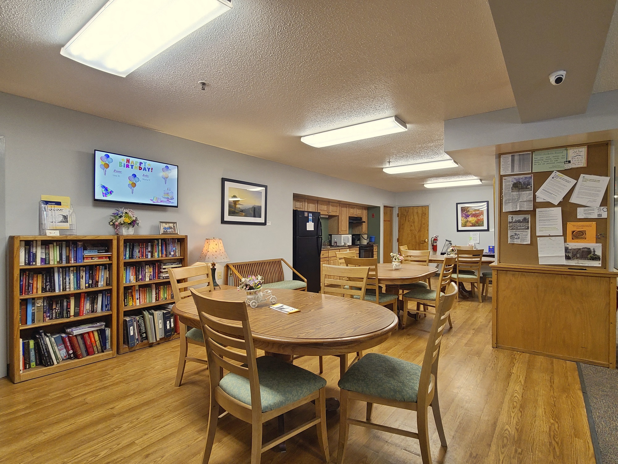 Community room with tables, chairs and bookcase