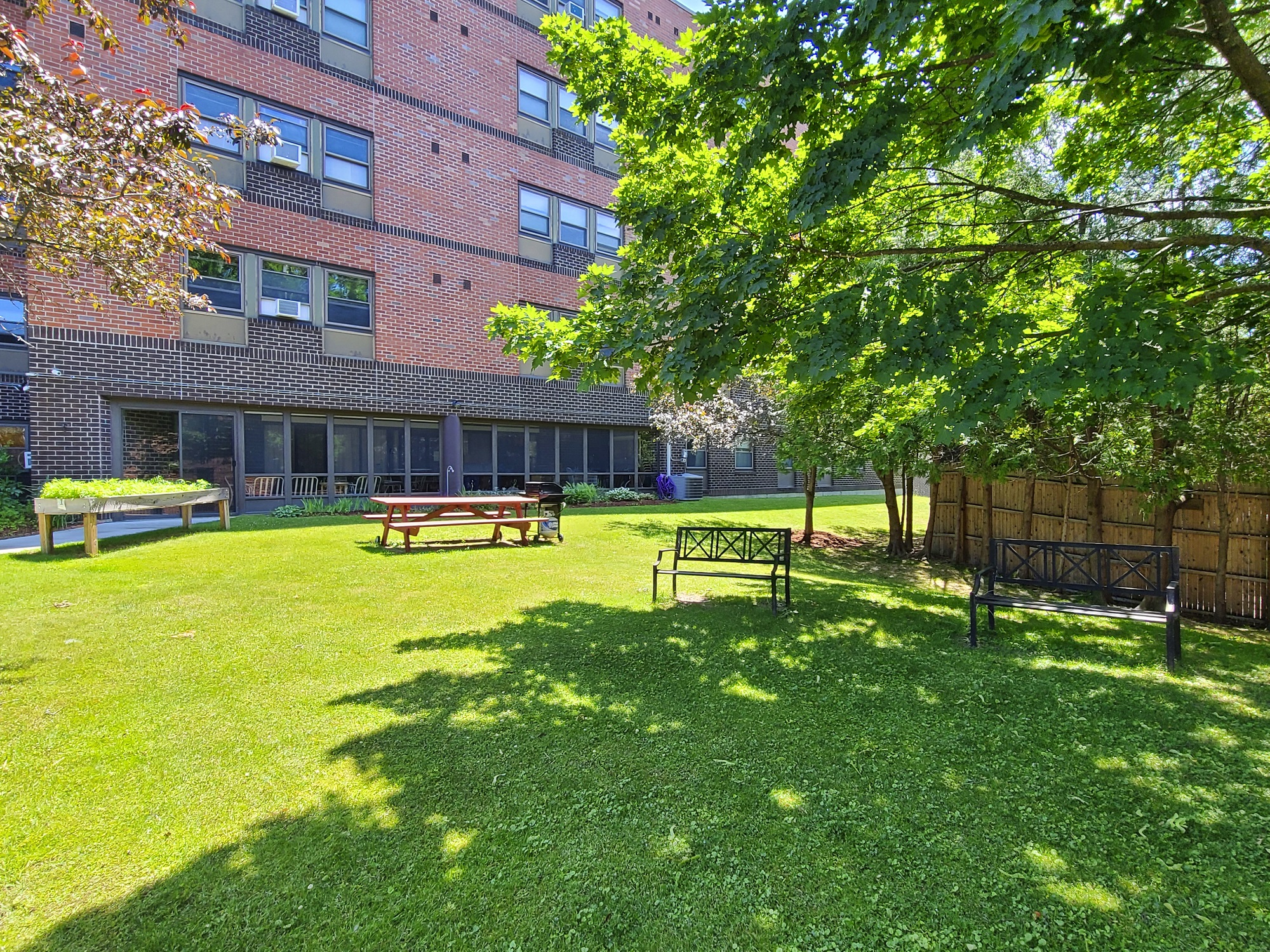 McKenzie House lawn in summer with picnic tables, benches and resident garden boxes