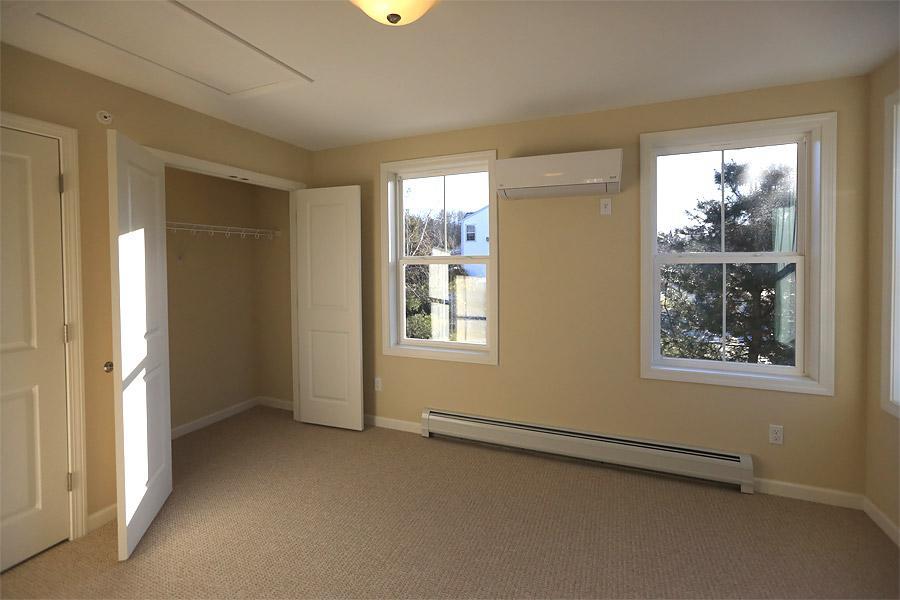 Carpeted rye bedroom with closet, extrior windows and wall mounted HVAC