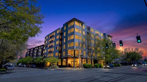 A large building with a lot of windows is lit up at dusk.