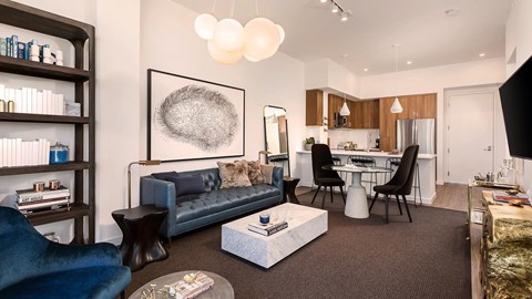 A modern living room with a blue couch and a grey abstract painting on the wall.