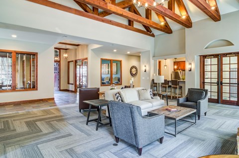A living room with a grey couch and a wooden ceiling.