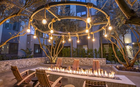 A fire pit in the middle of a patio surrounded by chairs.