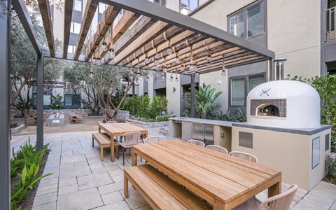 A patio with a table and chairs under a wooden pergola.
