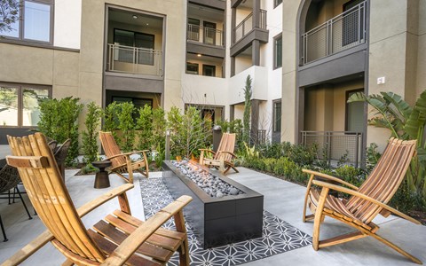 A patio with chairs and a fire pit in front of a building.