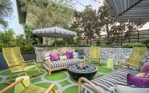 A patio with a fire pit and chairs.