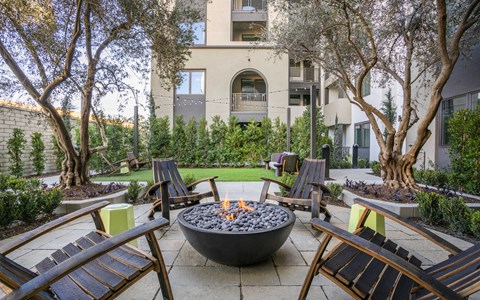 A fire pit sits in the middle of a patio surrounded by chairs.
