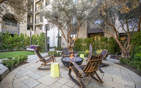 A patio with a fire pit and chairs.