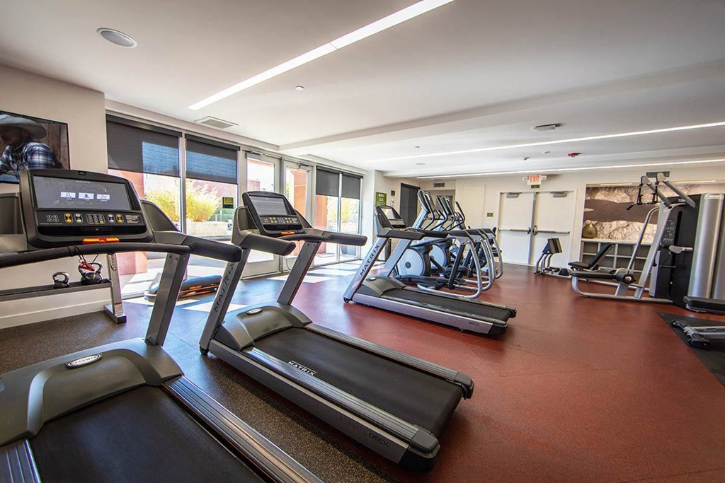 a gym with cardio equipment and windows in a building