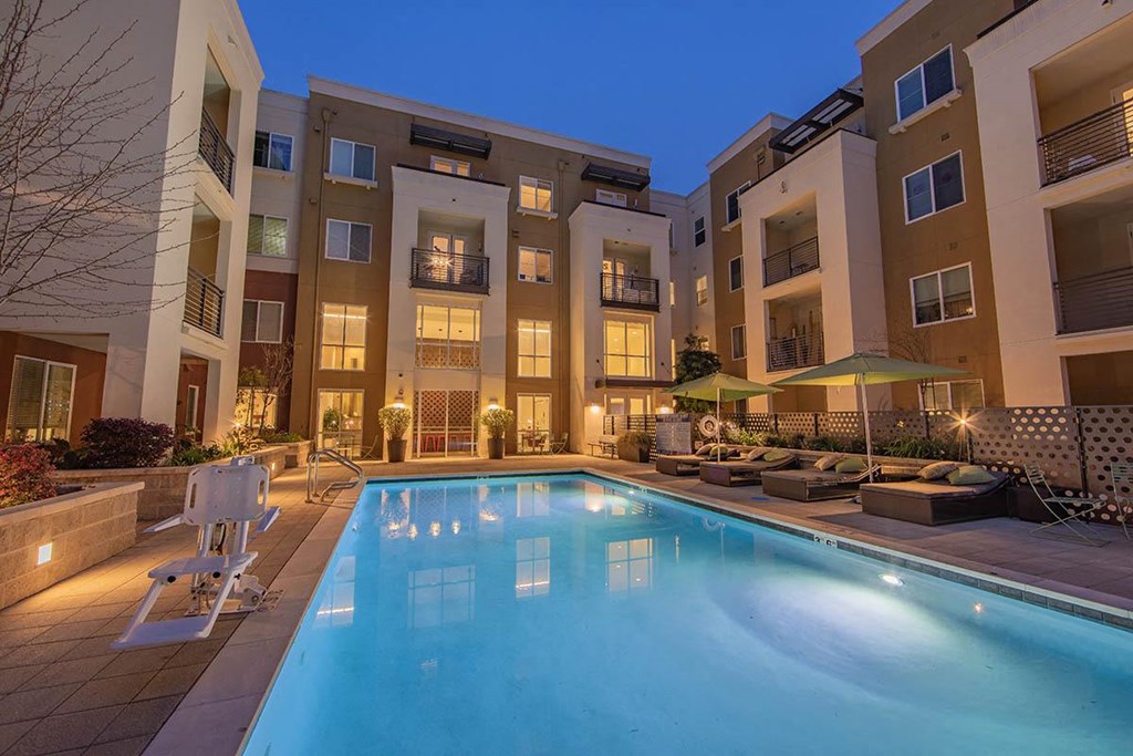 a swimming pool in front of an apartment building at night