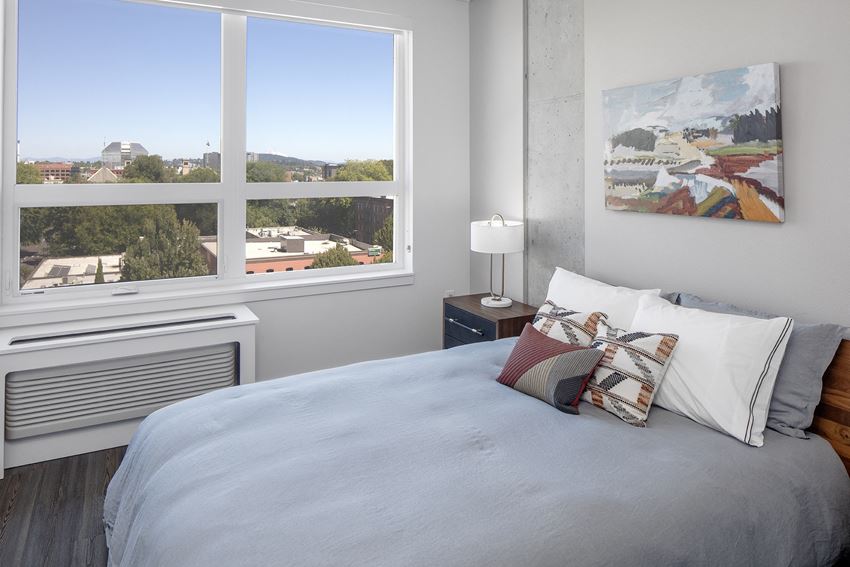 a bedroom with a large window and a bed with pillows
