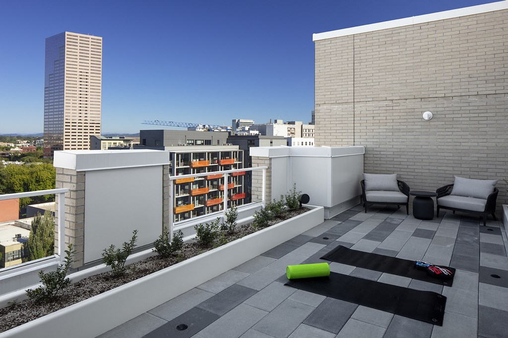 a roof terrace with a city in the background and two couches and chairs