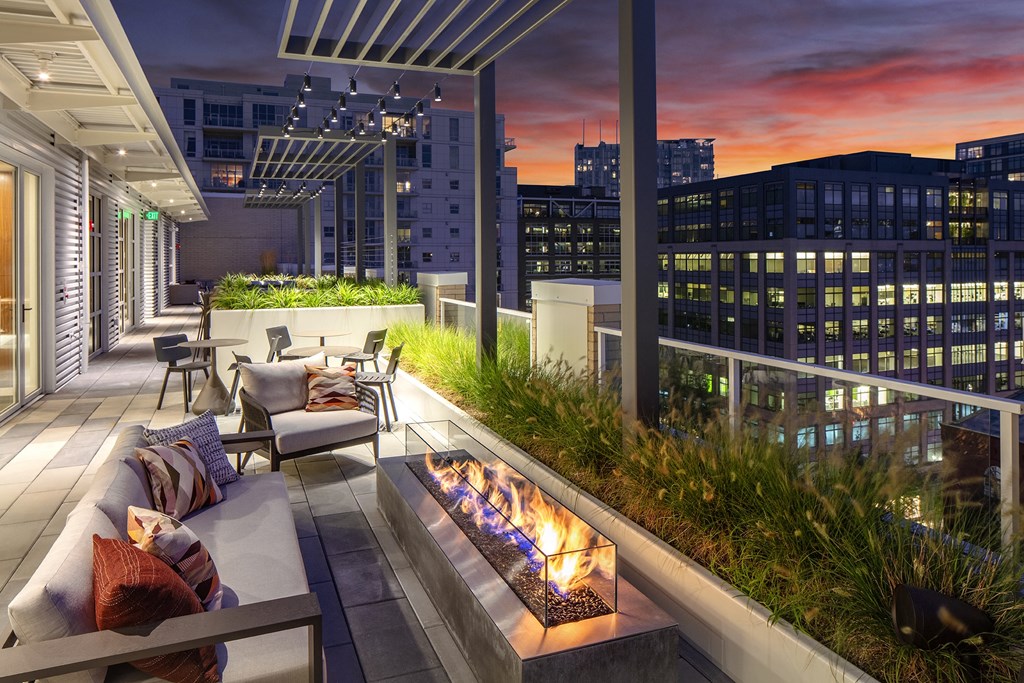 a terrace with a fireplace and a city skyline at night