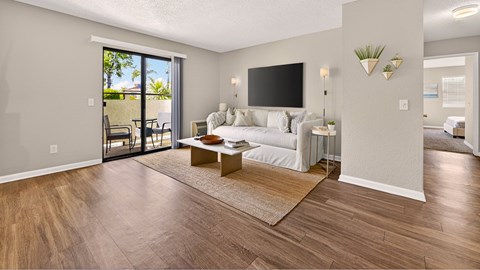 A living room with a white couch and a flat screen TV mounted on the wall.