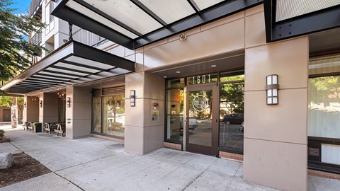 The image shows a modern building entrance with a glass door and a sign that reads "1601".