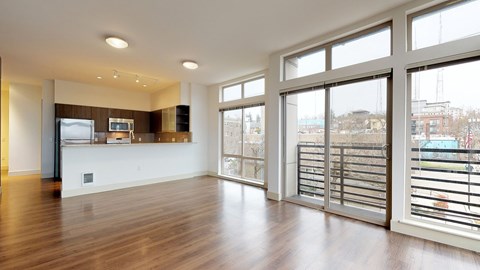 A spacious room with wooden floors and large windows overlooking a cityscape.