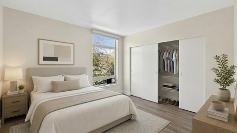 A bedroom with a large bed, a nightstand, a window with a view, a wardrobe, and a plant.