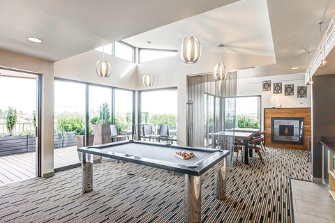 A pool table is in the middle of a room with a wood floor and a fireplace.