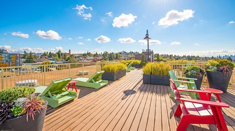 A wooden deck with red chairs and green plants.