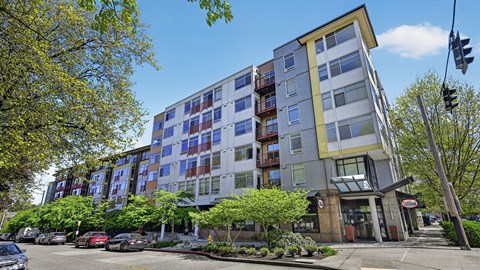 A modern multi-story apartment building with a parking lot in front.