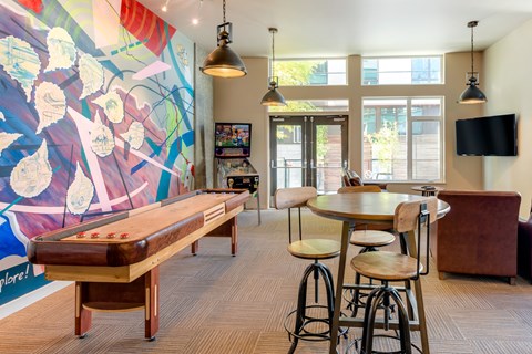 A room with a pool table, bar stools, and a television.