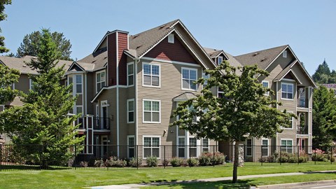 A large, multi-story residential building with a mix of beige and brown exterior walls.