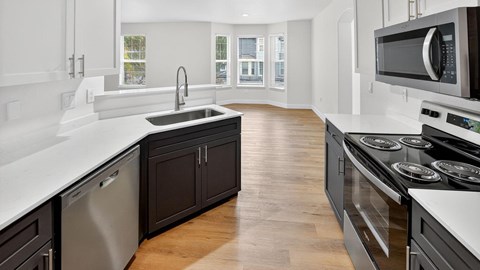 A modern kitchen with dark brown cabinets and white countertops.
