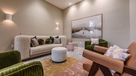 A living room with a white couch, green chairs, and a brown leather chair.