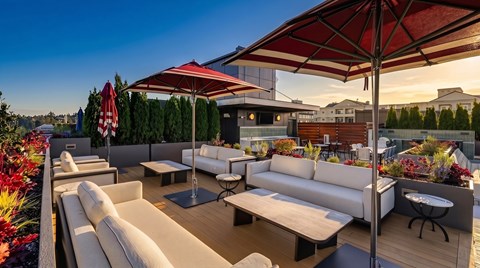 A patio with white furniture and red umbrellas.
