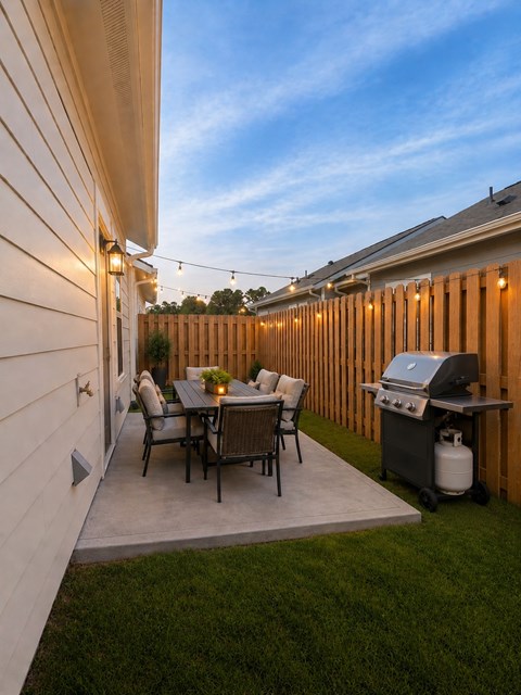 A patio with a table and chairs and a grill.