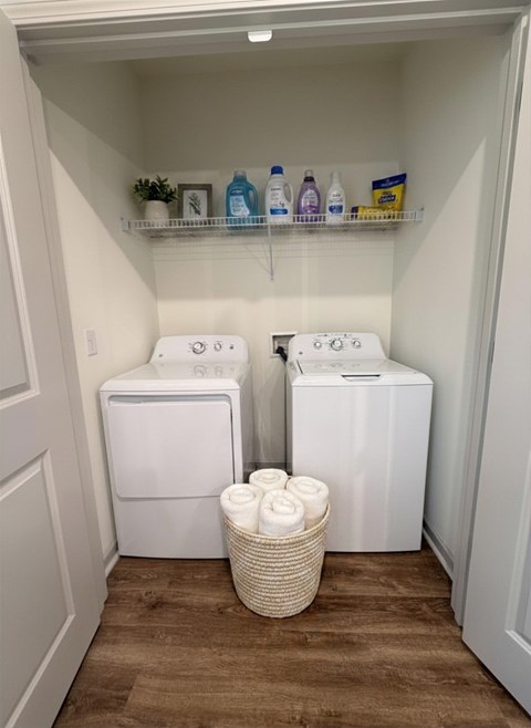 A small laundry room with a basket of towels in front of the washer and dryer.