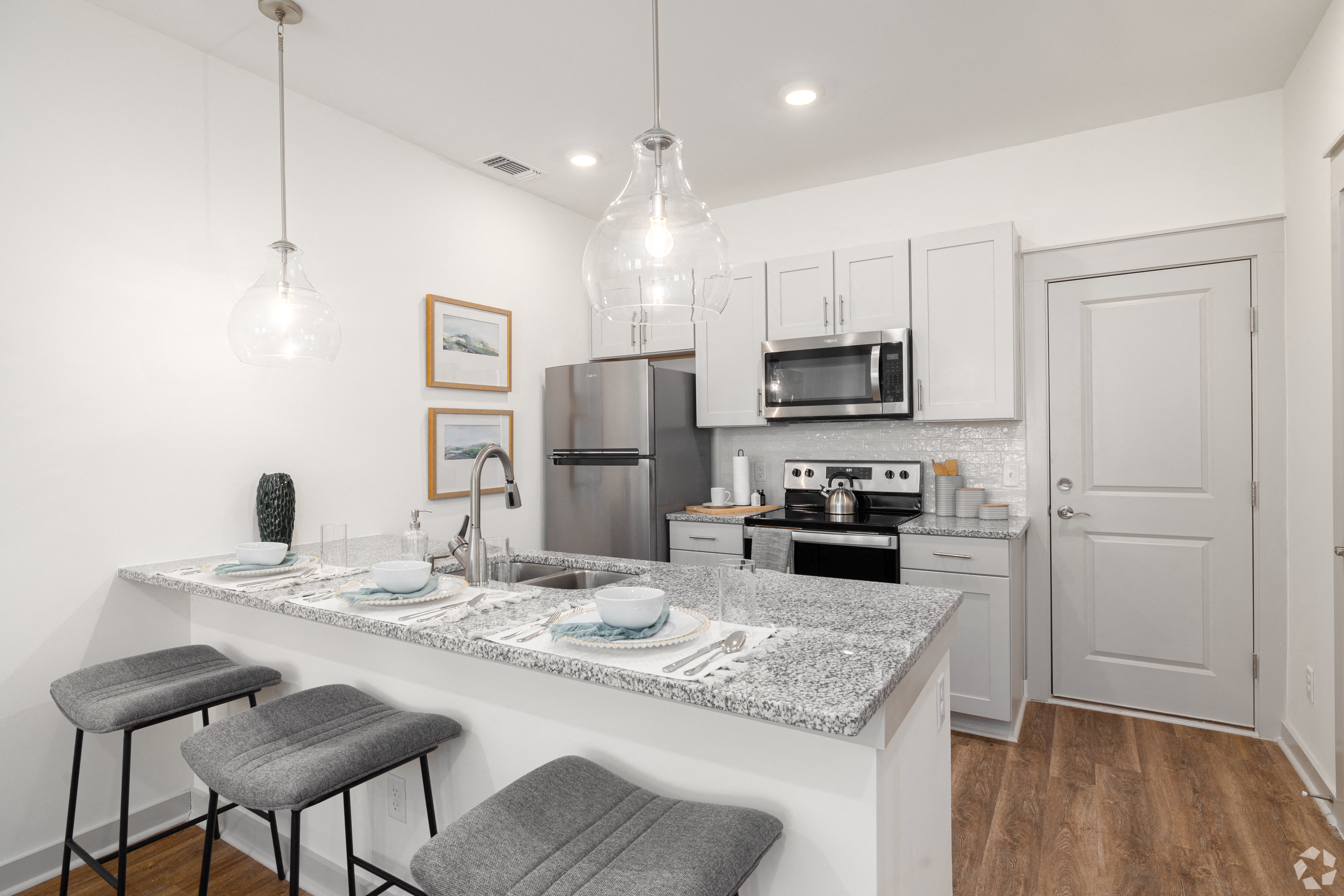 an open kitchen with a marble counter top and a bar with two stools