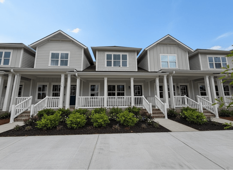 A row of houses with white railings and steps leading to the front doors.