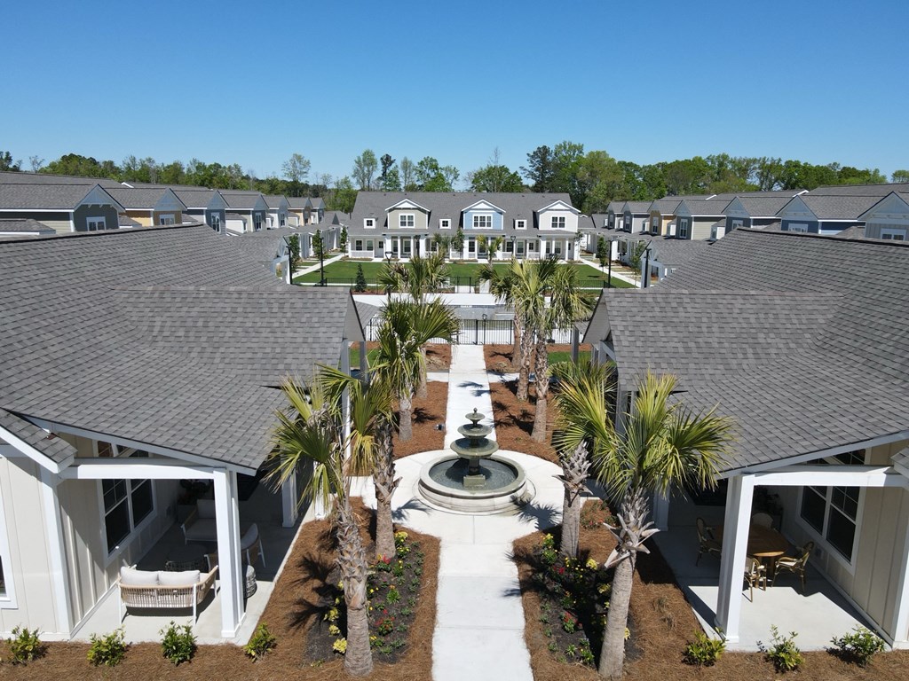 a fountain is in the center of a courtyard with houses at Allier Port Wentworth Apartments, Port Wentworth, GA, 31407